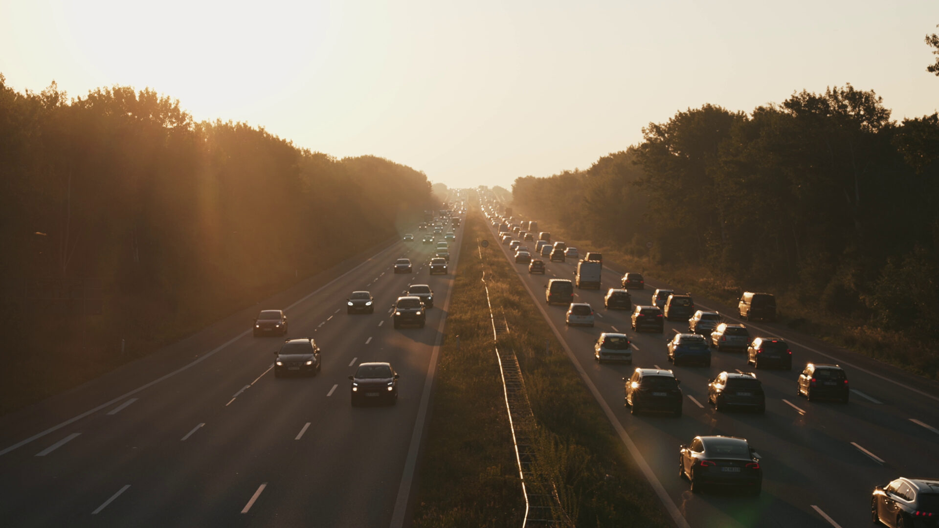 Heavy traffic on a highway at sunrise with cars moving in both directions, creating a traffic jam in the early morning mist.