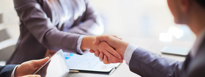 Close up of two people in business attire shaking hands