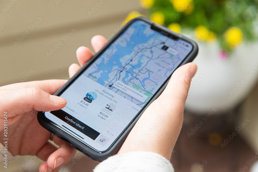 A person using the Uber app on their smartphone to book a ride, showing a map and ride options.