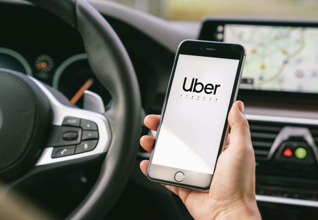 A person holding a smartphone with the Uber app open inside a car, representing rideshare services in Miramar, Florida.