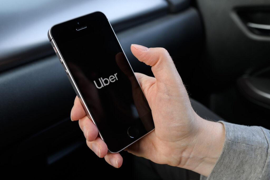 A person holding an iPhone with the Uber app open while sitting inside a car, representing rideshare services in Port St. Lucie, Florida.