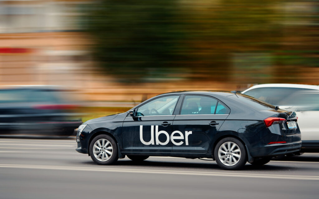 A black Uber vehicle in motion on a busy Miami street, representing the growing use of rideshare services in South Florida.
