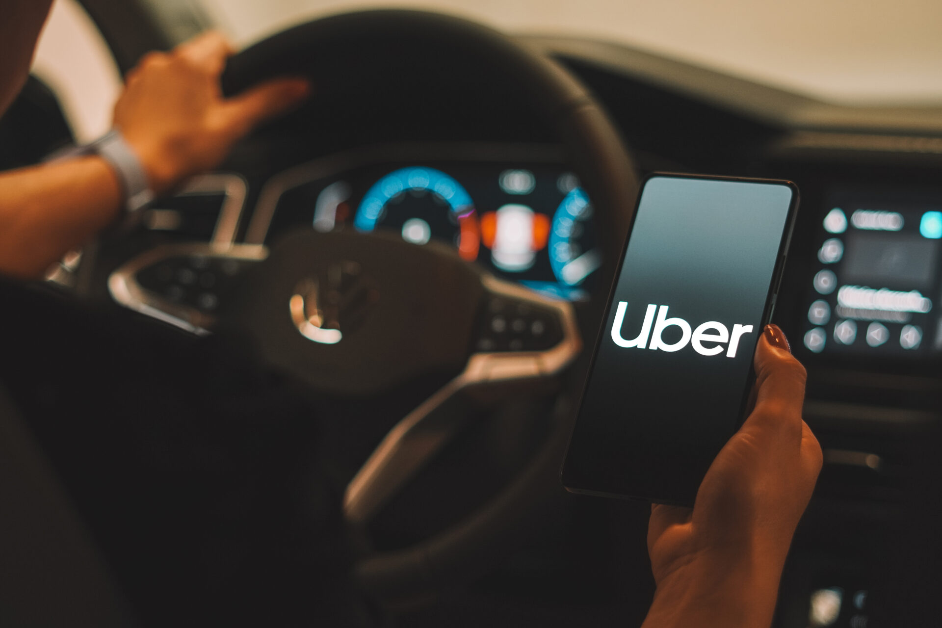 A driver holding a smartphone displaying the Uber app inside a vehicle, highlighting rideshare services in Jacksonville, Florida.