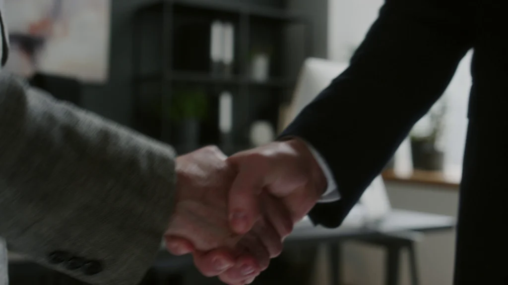 Close-up of two professionals shaking hands in an office, symbolizing trust and legal representation by a Plantation personal injury lawyer.
