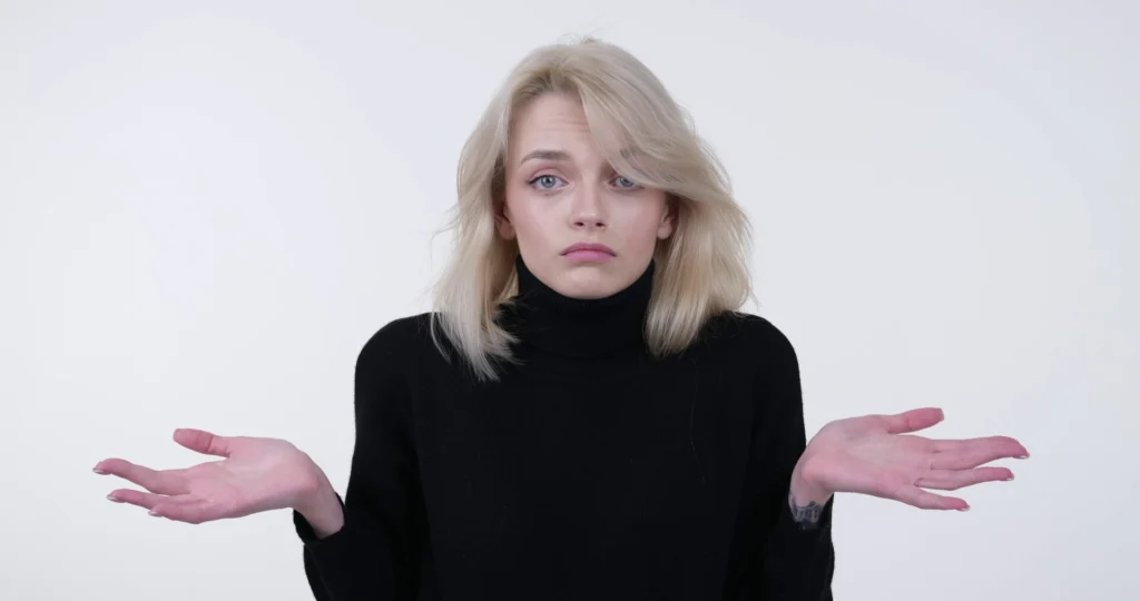 Confused person after Uber accident in Fort Lauderdale, raising hands in black turtleneck.