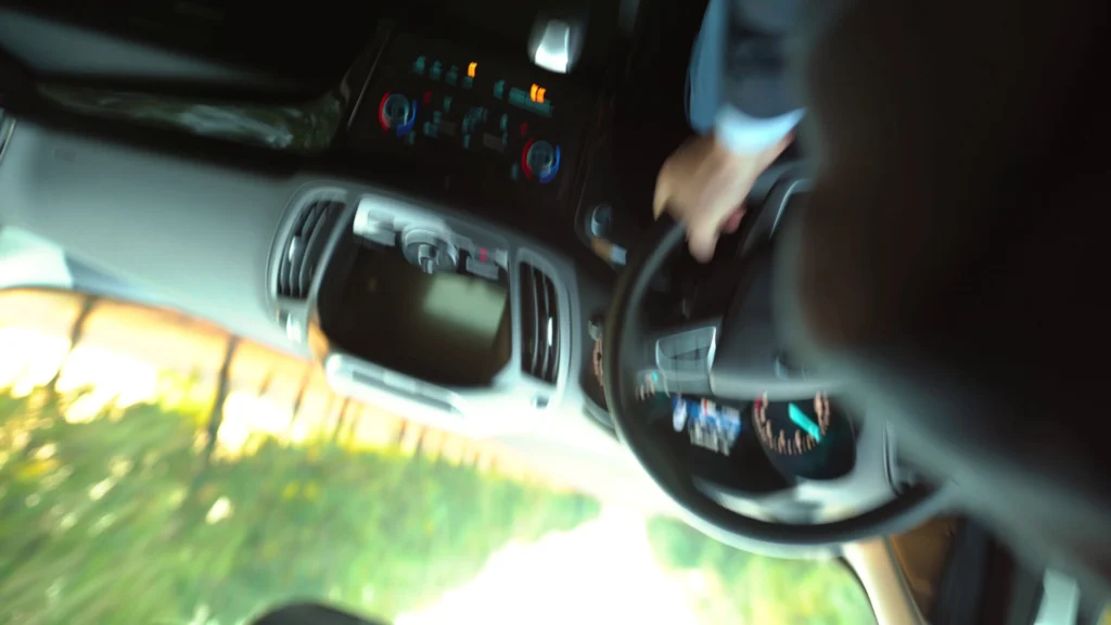 Blurry and tilted view of a driver gripping the steering wheel inside a moving car, suggesting a sudden loss of control.