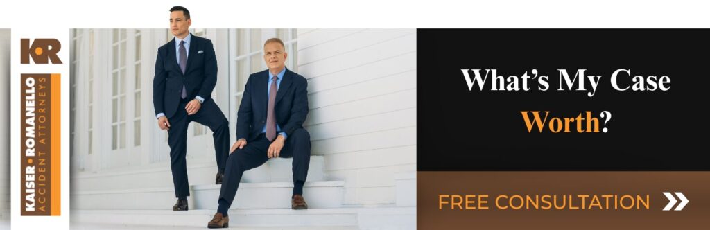 Two professional men in suits, one standing and one sitting on steps in front of a building, with text reading "What's My Case Worth?" and "FREE CONSULTATION" on an advertisement banner for Kaiser Romanello Accident Attorneys.