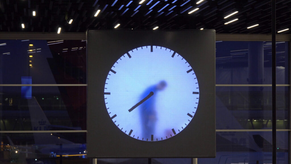 Large digital clock in an airport terminal with an airplane outside, symbolizing time limits for filing aviation accident claims.