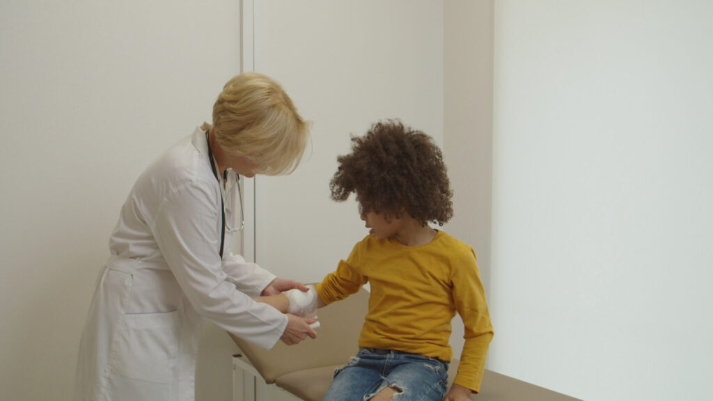 Doctor bandaging a child's arm wound in a medical clinic, illustrating immediate care after an injury like a dog bite.