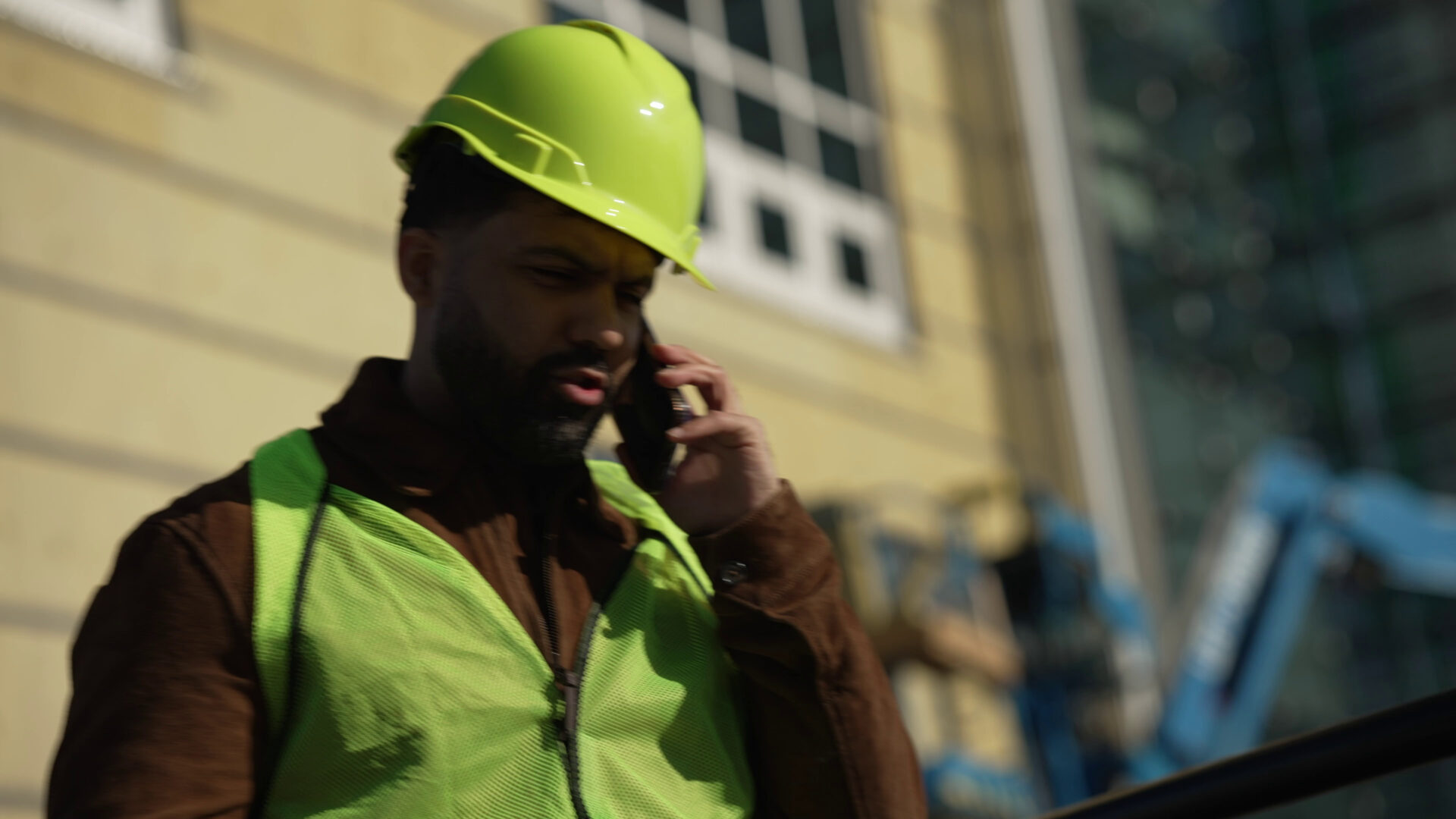 Concerned construction worker in green hard hat and vest calling for legal help after accident at Florida job site