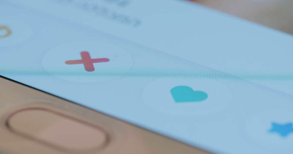 Close-up of a smartphone screen displaying dating app swipe icons, including a red X, teal heart, and blue star, representing potential risks in online dating encounters in Florida.