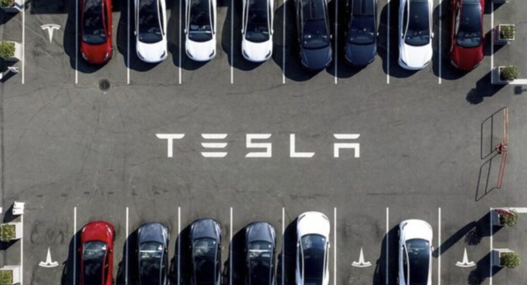 Aerial view of Tesla electric vehicles parked in a lot forming the company logo, illustrating risks in Florida Autopilot crash cases for car accident victims.