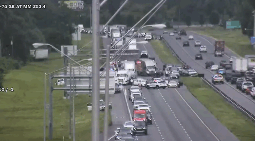 Traffic jam on I-75 southbound with multiple vehicles involved in a crash, emergency lights flashing, and lanes blocked.