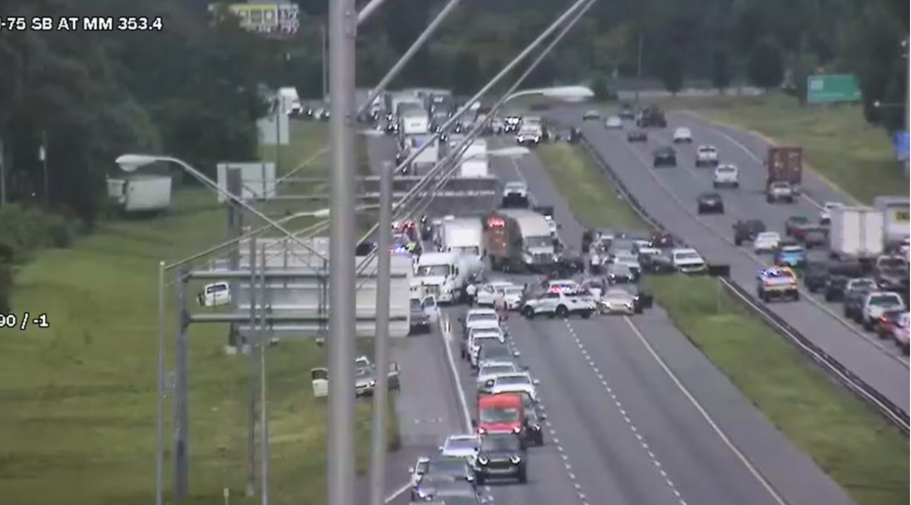 Traffic jam on I-75 southbound with multiple vehicles involved in a crash, emergency lights flashing, and lanes blocked.