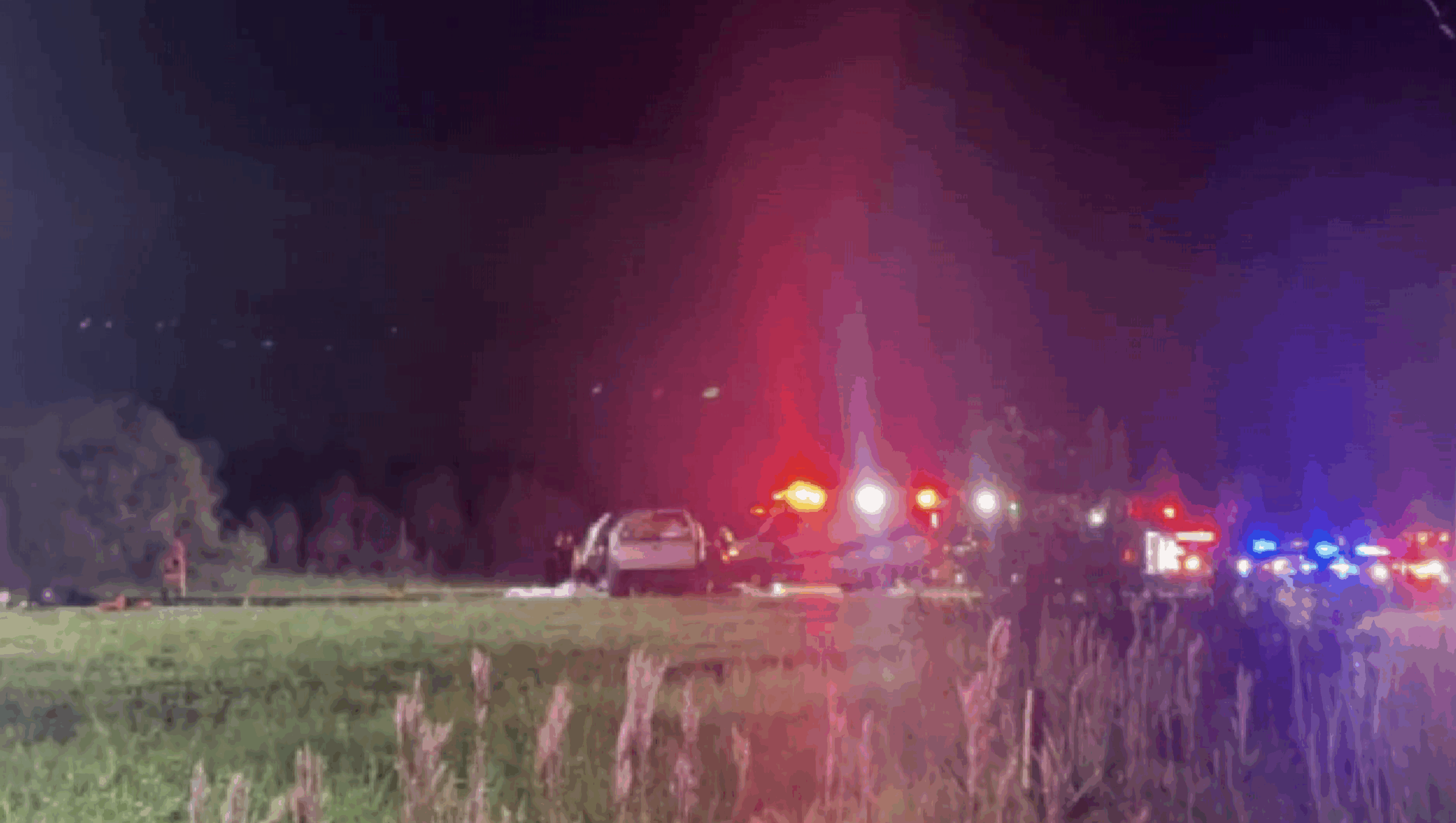 Emergency vehicles with flashing lights at a nighttime car accident scene on Burnt Store Road, Cape Coral, with a crashed SUV and police activity.