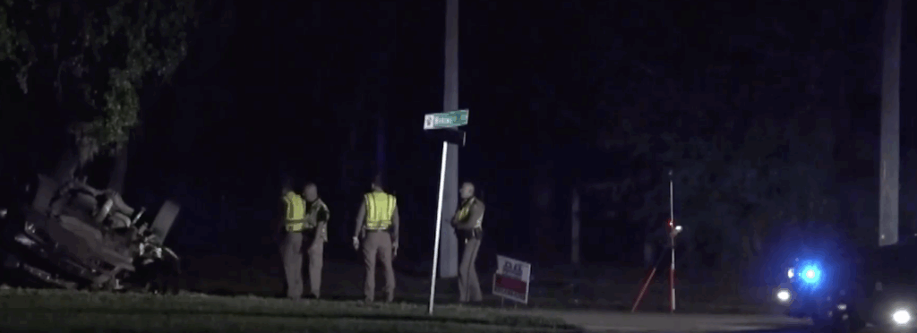 Overturned Chevrolet Silverado after fatal Apopka rollover crash at night; FHP troopers investigate near Wekiwa Drive sign.
