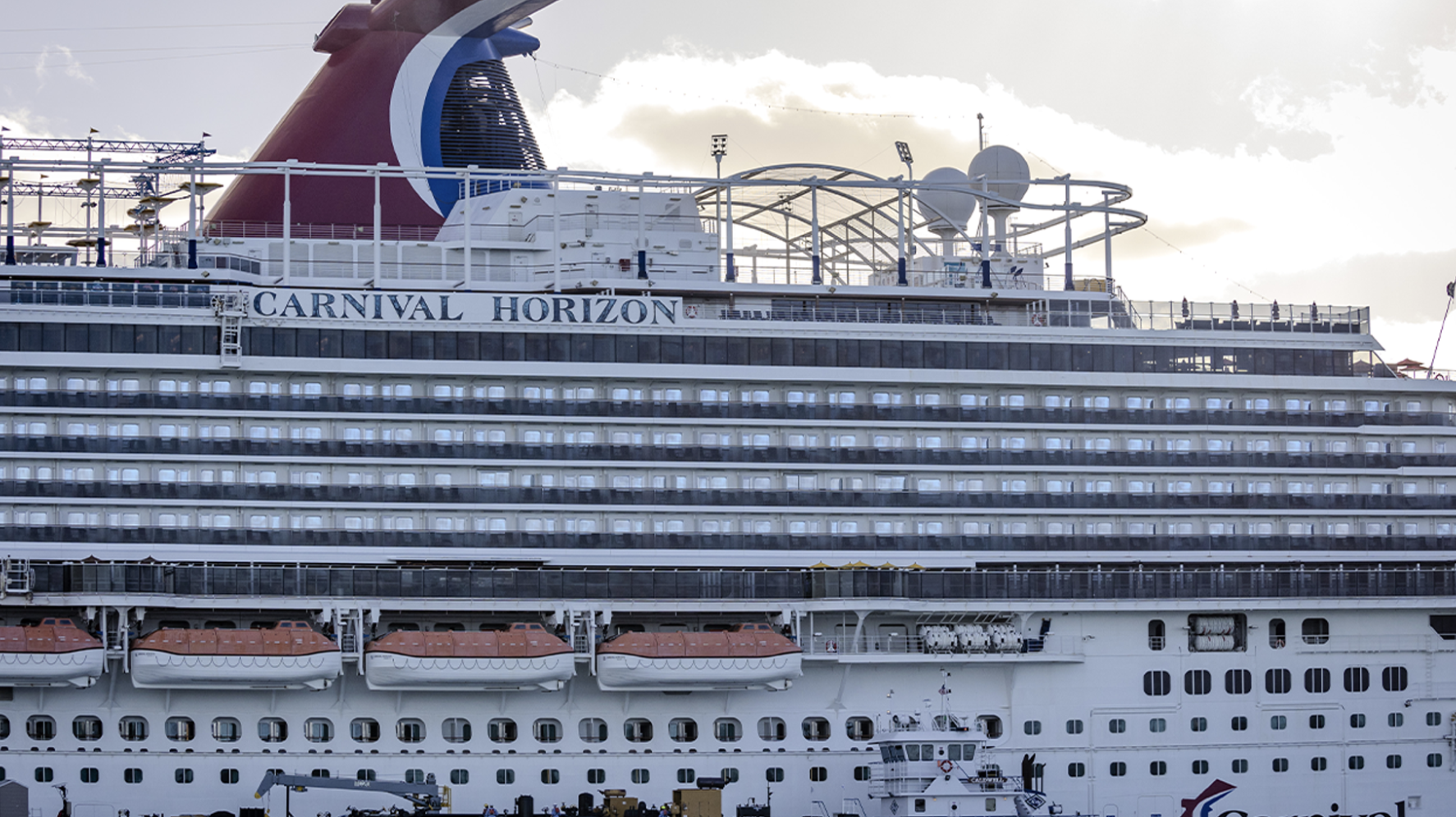 Carnival Horizon cruise ship docked with red whale-tail funnel and multiple decks visible.