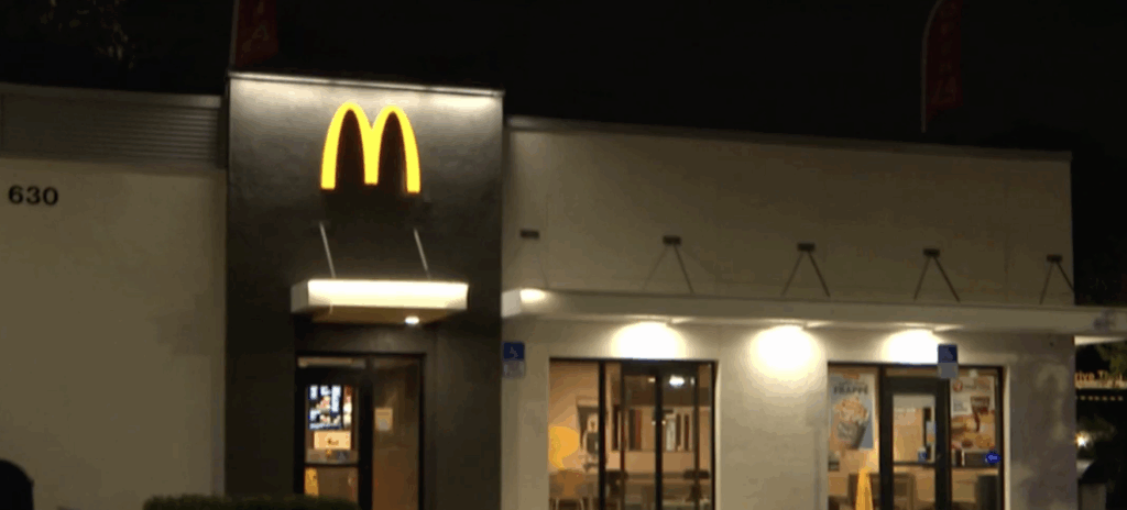 Nighttime view of the illuminated McDonald’s golden arches at the 24-hour restaurant located at approximately 630 West Sample Road in Pompano Beach, Florida, site of the fatal shooting on November 25, 2025.