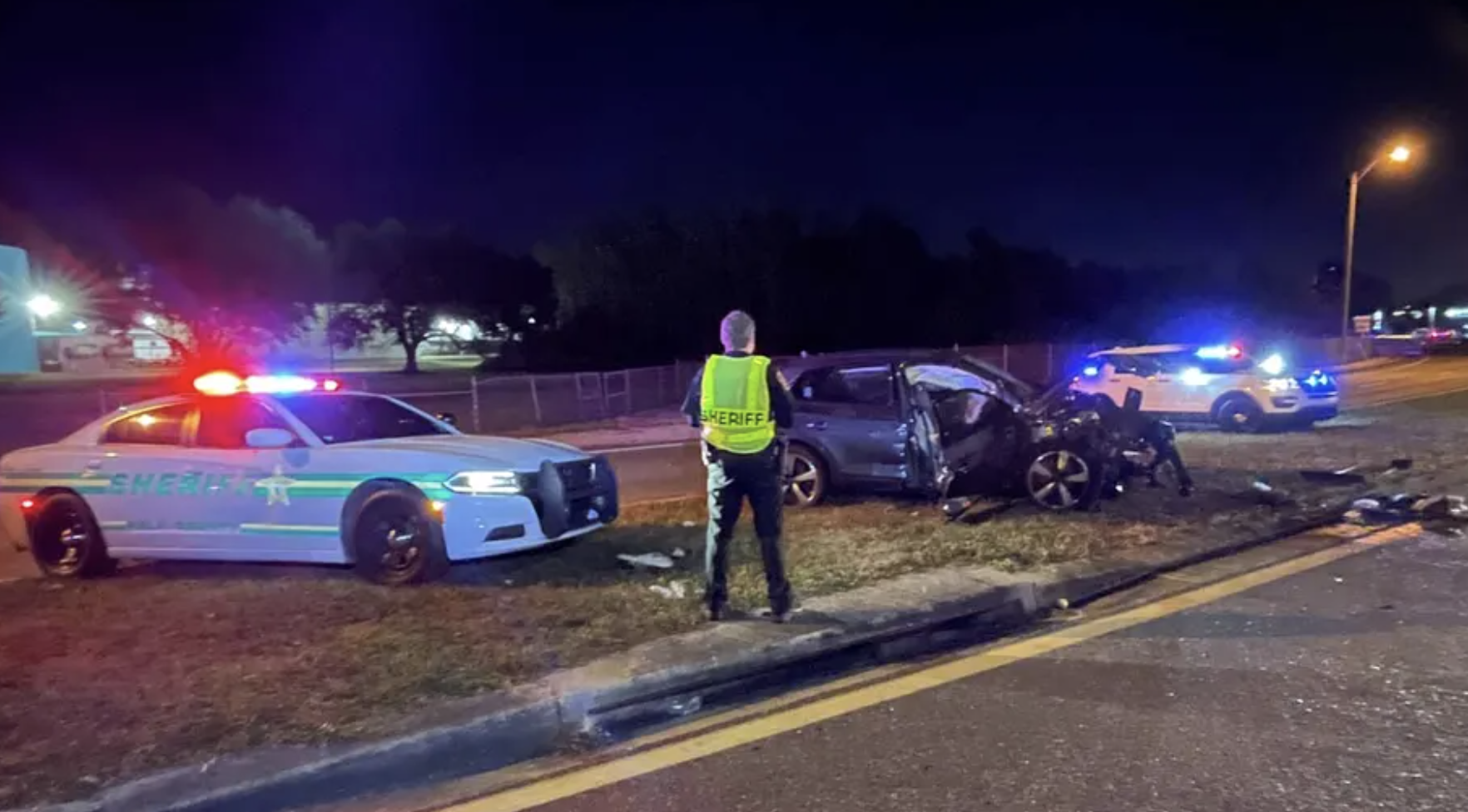 Scene of fatal multi-vehicle crash on Kathleen Road in Lakeland, FL with Polk County Sheriff vehicles and wreckage at night.