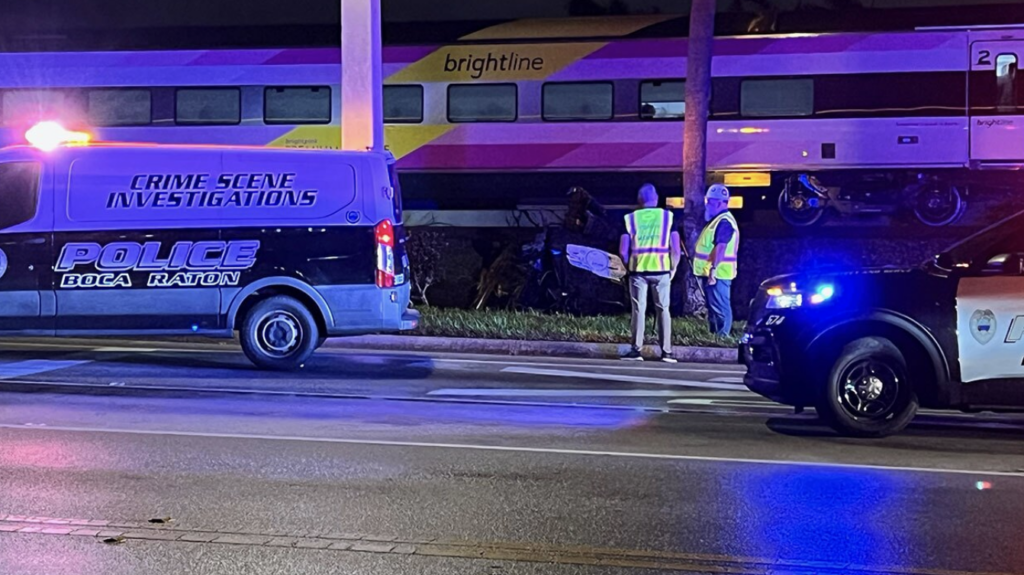 Boca Raton Police Crime Scene Investigations van and emergency responders at the scene of a night-time collision involving a Brightline train and a vehicle.