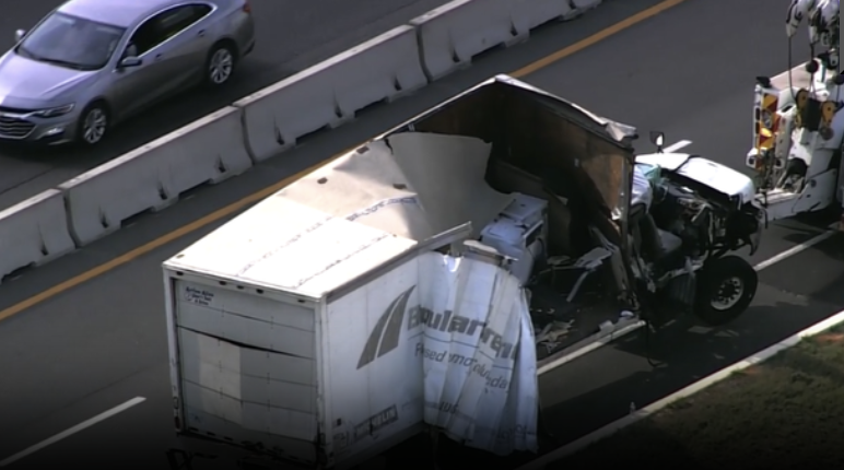 Severely damaged white box truck being towed after a multi-vehicle highway crash in Lake County.