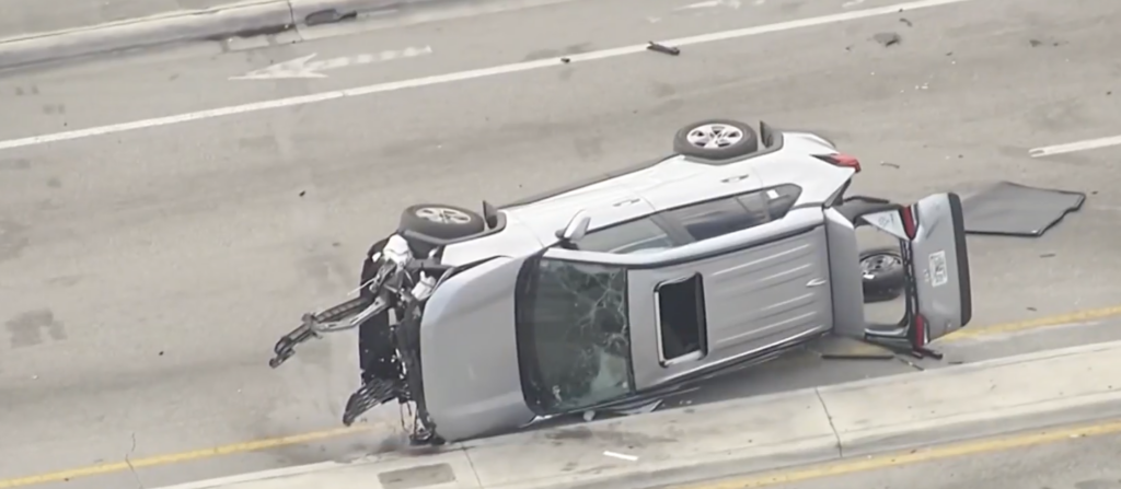 Aerial view of overturned silver SUV on road median after multi-car crash in West Little River Miami-Dade