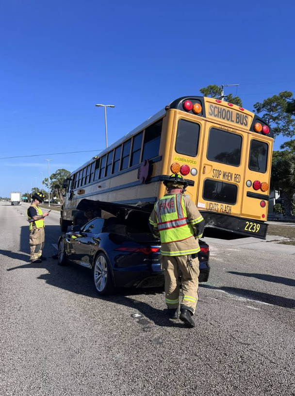 Black Jaguar wedged underneath the rear of Lee County school bus 2239 as firefighters respond to the crash scene on US-41 in San Carlos Park Florida