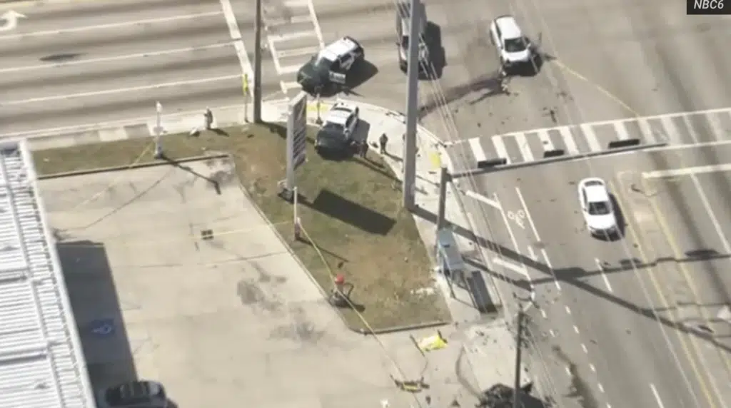 Aerial view of fatal multi-car crash scene at NW 103rd Street and NW 7th Avenue in Miami-Dade County showing damaged vehicles near a bus stop with debris scattered across the intersection