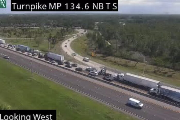 FDOT Florida 511 traffic camera image showing northbound traffic backed up on Florida's Turnpike near mile marker 134.6 in Martin County during the Monday afternoon fatal crash investigation, with semi-trucks and passenger vehicles stopped in both right lanes