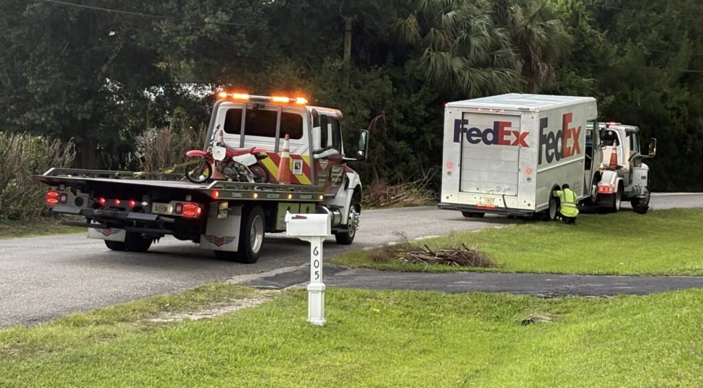 Tow trucks remove a red dirt bike and a FedEx box truck from the scene of a fatal crash on East Midway Road in Fort Pierce